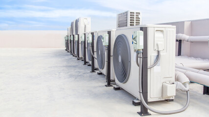 Air conditioning (HVAC) on the roof of an industrial building with blue sky and clouds.	