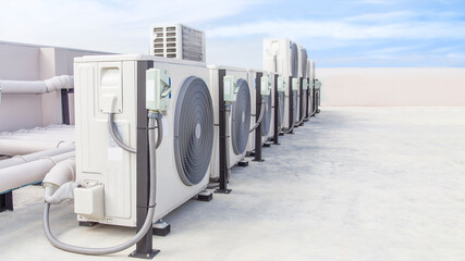 Air conditioning (HVAC) on the roof of an industrial building with blue sky and clouds.	