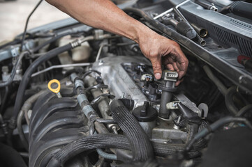Auto mechanic testing an engine ignition coil on a Car. - obrazy, fototapety, plakaty