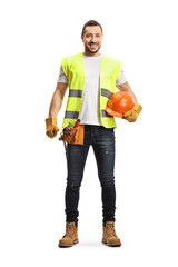 Full length portrait of a construction worker holding a helmet, wearing a tool belt and smiling at camera