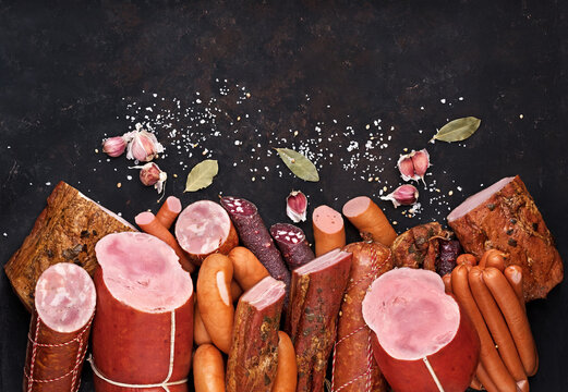 assortment of meat products including sausage ham bacon spices garlic on a black background view from the top. Boiled Ham Meatworks Product Photo
