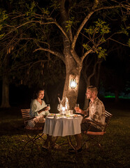 couple on safari in South Africa, Asian women and European men having a bush dinner with...