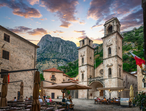 Church of Saint Tripuna in the old town of Kotor.Montenegro. Evening view of the Cathedral of Saint Tryphon with surrounding buildings and restaurants and mauntain in the background.