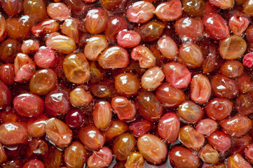 Close-up shot of red ripe gooseberry jam in sweet syrup.