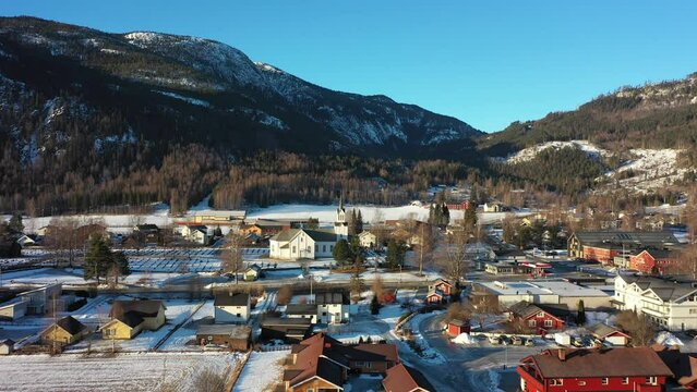 Approaching Nesbyen church in Hallingdal Norway during beautiful morning sunlight - Golden hour aerial with winter landscape surroundings