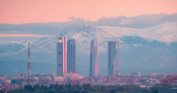 Timelapse of Madrid 5 towers skyline and snowy sierra mountain during sunrise