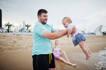 Summer vacations. Parents and people outdoor activity with children. Happy family holidays. Father, pregnant mother, baby daughter on sea sand beach.