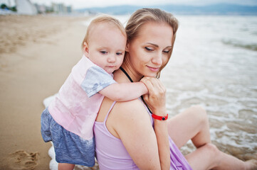 Fototapeta na wymiar Summer vacations. Parents and people outdoor activity with children. Happy family holidays. Mother with baby daughter on sea sand beach.