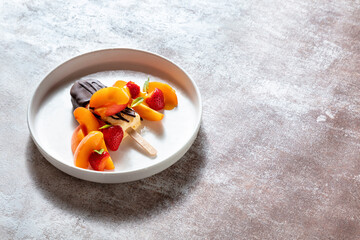 Ice cream on a stick in dark chocolate with peaches