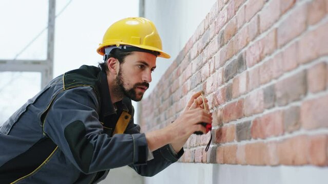 Charismatic constructor worker at construction site with safety helmet working concentrated he make measurements at new wall building