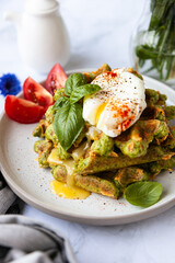 green spitato waffles with poached egg and tomatoes. breakfast on a light background. the concept of healthy eating, proper nutrition, comfort food, farm products