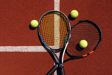 Tennis racquets with tennis balls on clay court.