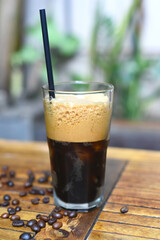 Cold americano with coffee beans  on wooden table