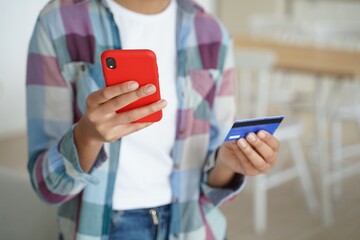 Female holding bank credit card, phone, uses banking services, e-bank apps, paying purchases online