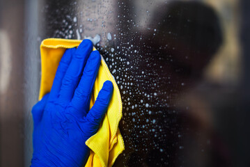 A woman or man washes a window at home. House cleaning. Washing dirty window glass detergent for...