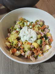 olivier salad in a white bowl in the kitchen