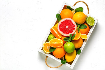 Fresh citrus fruits with leaves: lemons, oranges, mandarins, grapefruit, lime in wooden box