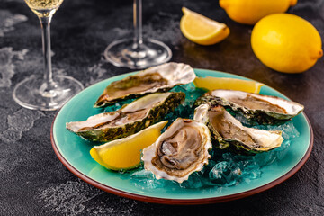 Opened fresh oysters on a blue plate, served with lemon and ice.