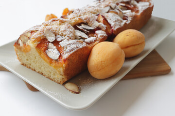 rectangular appetizing homemade apricot pie on a rectangular plate, on a wooden cutting board closeup