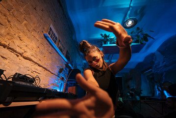Beautiful female DJ dancing to techno in a small club