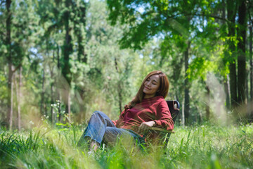Portrait image of a beautiful young asian woman with closed eyes sitting on a chair in the park
