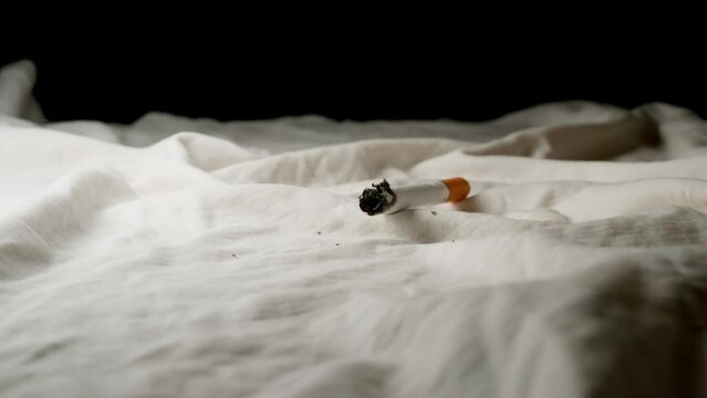 SLOW: Cigarette falls on a bed at home