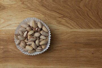 unpeeled pistachio on wooden background, top view