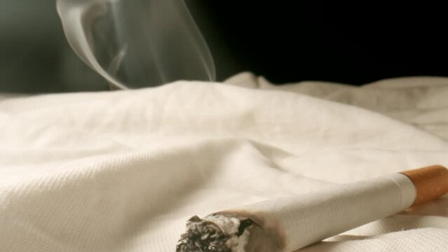 MACRO: Cigarette smoking on a bed at home - Dolly shot