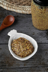 Old mustard on a white plate in rustic background