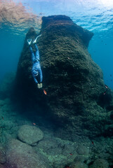 Freediver diving close to a big rock