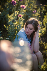 Young woman is posing in poppy field in cute blue dress