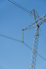 Fragment of metal pole of high-voltage power line VL-750 kV against blue sky. Close-up. There are more than 20 insulators in garland. Garlands of insulators are made of glass.