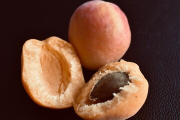 whole and halves of a ripe apricot on a black background