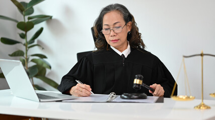 Concentrated senior judge in robe gown uniform having video conference, providing law consultation...