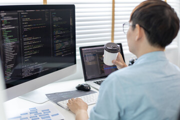 Professional development programmers are sipping coffee in a private office, Working on coding or programming on a computer, Write information or code for the website,  HTML, Javascript, Software.