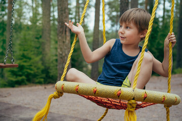 cute little boy having fun on a swing at playground