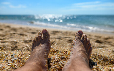 Men's feet on the background of the sea. Sea vacation concept. Selective narrow focus.