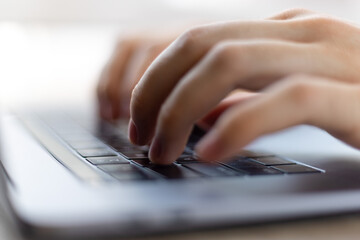 Closeup image of a man working and typing on laptop computer keyboard.