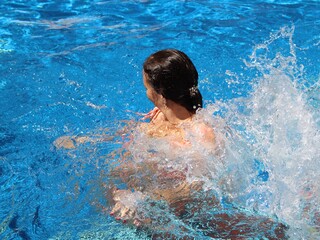 attractive girl having fun and splashing in the pool