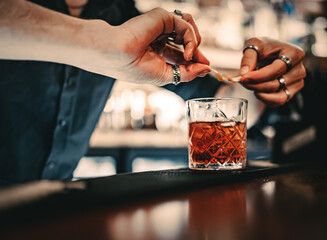 man bartender hand making negroni cocktail. Negroni classic cocktail and gin short drink with sweet...