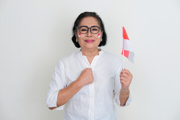 Indonesian elderly woman holding nation flag with one clenched fist on her chest