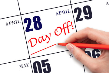 Hand writing text DAY OFF and drawing a line on calendar date 28 April. Vacation planning concept.