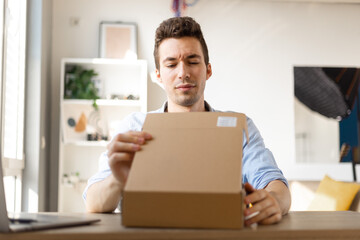 Angry irritated young caucasian man dissatisfied by received parcel, unhappy customer unpacking...