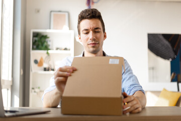 Angry irritated young caucasian man dissatisfied by received parcel, unhappy customer unpacking...