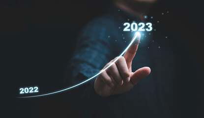 Businessman hand drawing for increasing arrow from 2022 to 2023 for preparation merry Christmas and happy new year concept. - obrazy, fototapety, plakaty