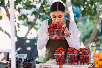 Young positive saleswoman at work, holding strawberries in her hands - 519762304
