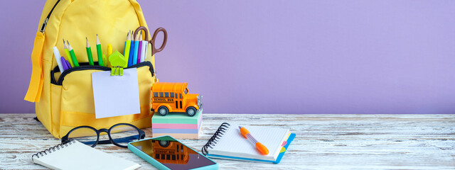 Banner. Concept back to school. Full tyelllow School Backpack with stationery on table.