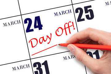 Hand writing text DAY OFF and drawing a line on calendar date 24 March. Vacation planning concept.