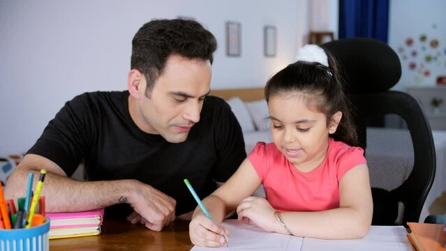 A sweet adorable girl studying with her father - happy parenting  togetherness and relationship  Indian single father . A caring Indian dad helping his little girl with her holiday homework - schoo...