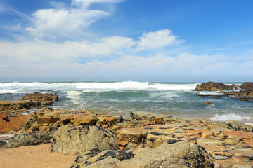 Fototapeta na wymiar A beach view with rocks, sea and sky, space for text